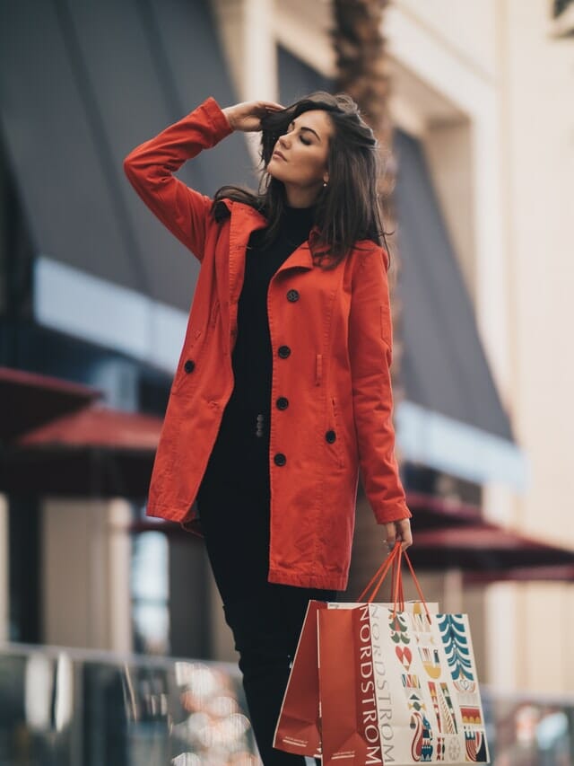 vrouw met winkeltassen en een rode jas