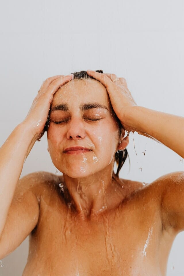 vrouwe die shampoo aanbrengt in de douche